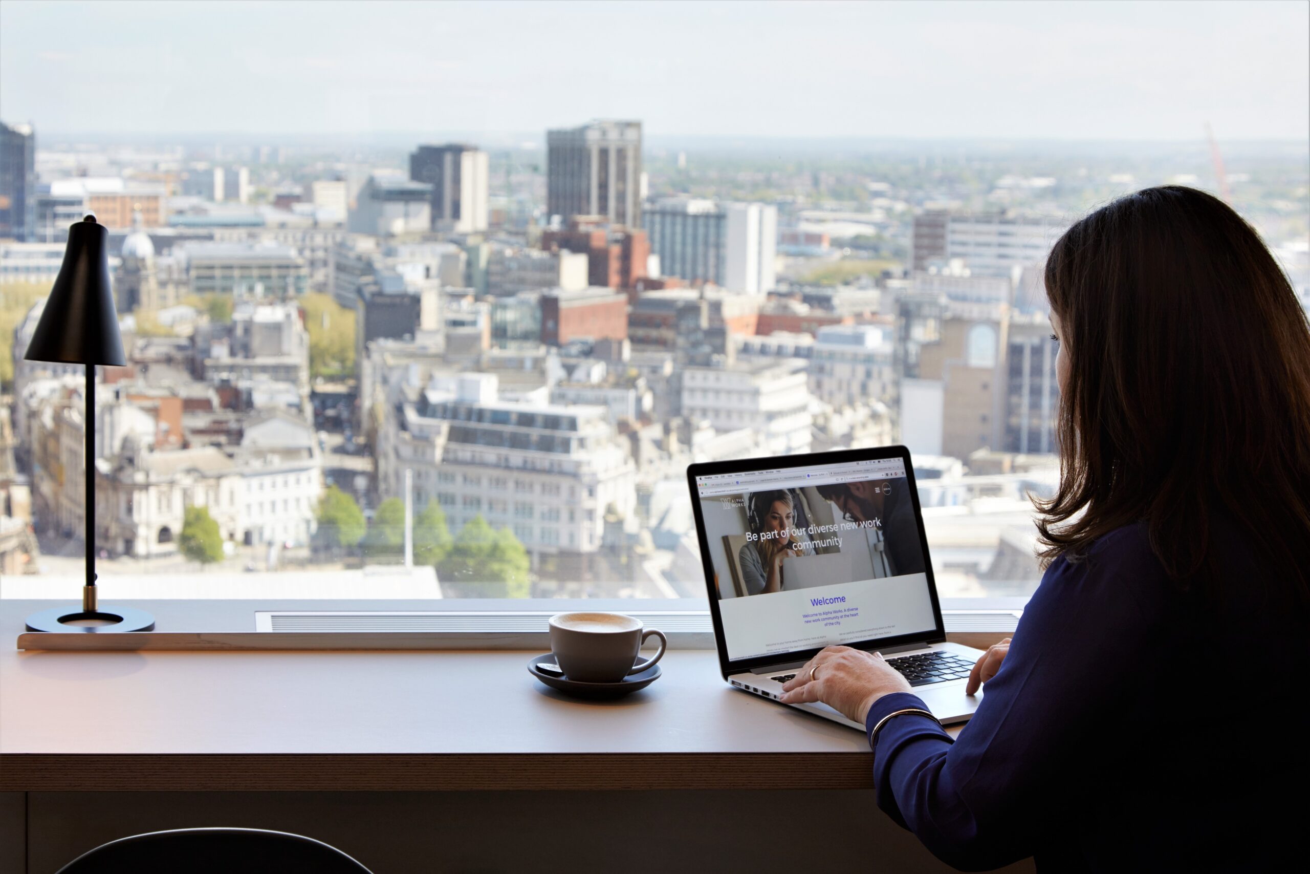 Person using a laptop beside an office window